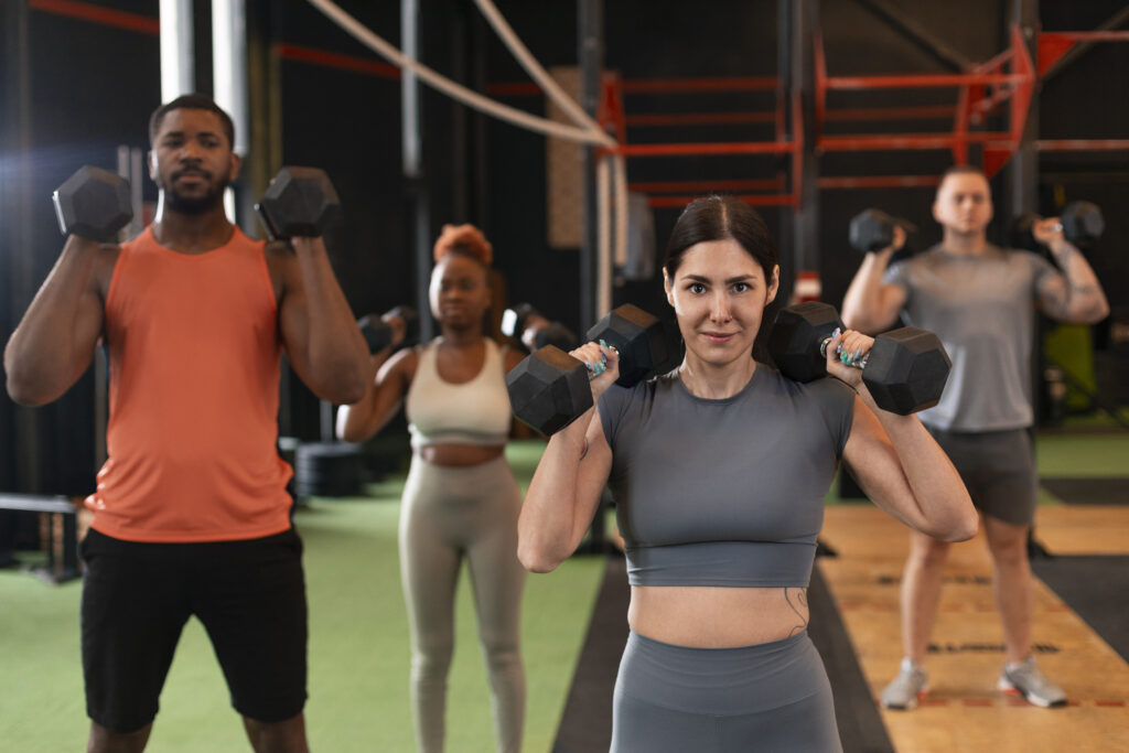 Groupe de participants suivant un cours collectif en salle de sport à Yvetot, encadrés par un coach